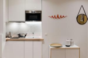 巴黎SUITE ELUARD au cœur de la Rive Gauche, neuf, design, 2-4 personnes的白色的厨房配有水槽和微波炉
