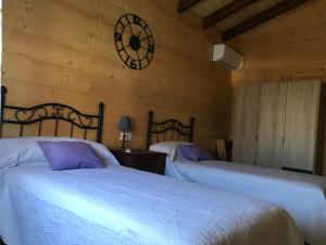 马德里德霍斯Casa rural Vega alta的一间卧室设有两张床,墙上挂着一个时钟。