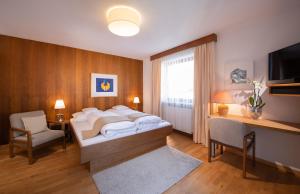 厄茨Appartements Falkner Dorli的一间卧室配有一张床、一张书桌和一台电视