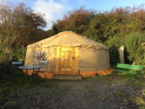 WhitegateInch Hideaway Eco Camping的圆顶帐篷配有桌子和绿色长凳