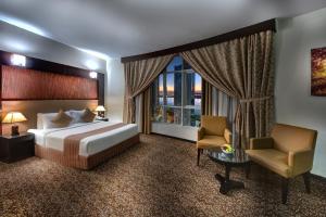 沙迦阿雅那酒店的卧室配有床、椅子和窗户。