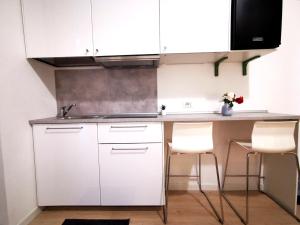 米兰Modern Studio Apartments的白色的厨房配有白色橱柜和白色椅子