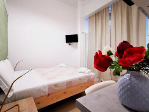 米兰Modern Studio Apartments的一间卧室,配有一张床,一张桌子上放着玫瑰花瓶
