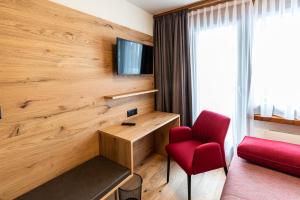利德阿尔卑斯银沙酒店及餐厅的酒店客房设有红色椅子和电视
