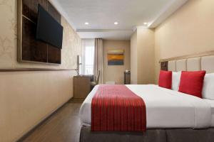 比什凯克Ramada by Wyndham Bishkek Centre的酒店客房配有一张带红色枕头的大床