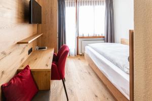 利德阿尔卑斯银沙酒店及餐厅的一间卧室配有一张床、一张桌子和红色椅子