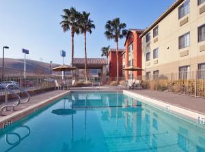 Westley韦斯特利智选假日酒店的棕榈树建筑前的游泳池