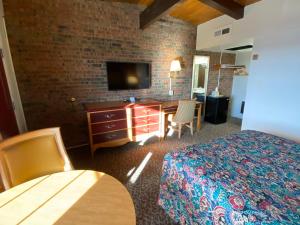 阿拉莫萨Dunes Inn Alamosa的酒店客房配有一张床、一张书桌和一台电视。