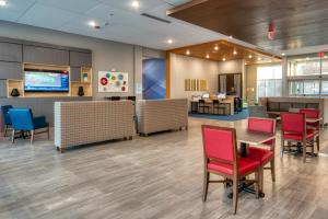 奥马哈Holiday Inn Express & Suites - Omaha Downtown - Airport, an IHG Hotel的医院的大厅,有红色的椅子和桌子