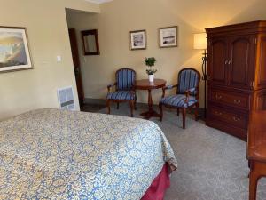卡梅尔诺曼底旅馆的卧室配有一张床和一张桌子及椅子