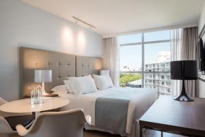 蒙得维的亚Vivaldi Hotel Loft Punta Carretas的酒店客房设有床、桌子和窗户。