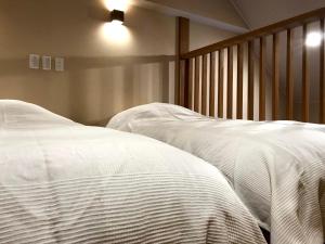 野沢野泽温泉乌托邦酒店的卧室内的两张床,配有白色床单