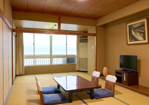 和歌山新瓦卡日式旅馆的客厅配有桌椅和电视。
