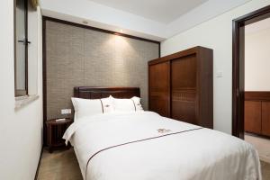 三亚三亚海棠湾艾栖洋房别墅的卧室配有一张白色大床和木制床头板