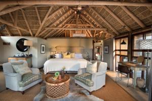 格拉罕镇Kwandwe Great Fish River Lodge的一间卧室配有一张床、两把椅子和一张桌子