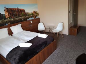 OsielskoPro Bed & Breakfast的一间卧室配有一张大床和两张白色椅子