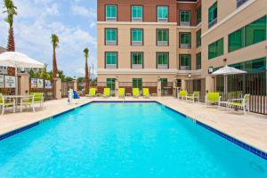 休斯顿Holiday Inn Express & Suites Houston S - Medical Ctr Area, an IHG Hotel的酒店前的游泳池配有椅子和遮阳伞