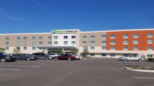 坦帕Holiday Inn Express & Suites - Tampa East - Ybor City, an IHG Hotel的停车场内停放汽车的大型建筑