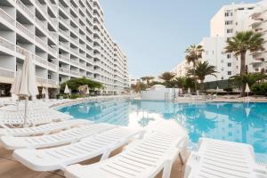 美洲海滩Palm Beach - Excel Hotels & Resorts的一座带白色躺椅的游泳池,位于大楼旁