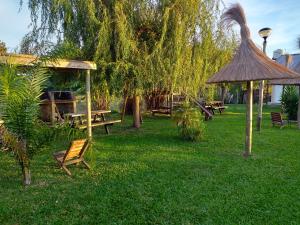 GualeguaychúAitue Bungalows的一个带长椅、野餐桌和树的公园