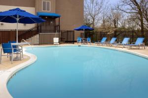 大学公园市大学公园智选假日套房酒店 - 大学区的一个带蓝色椅子和遮阳伞的大型游泳池