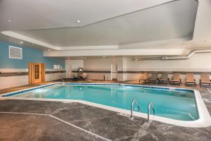 乔利埃特Holiday Inn Hotel & Suites - Joliet Southwest, an IHG Hotel的一座大型游泳池,位于酒店客房周围,配有椅子
