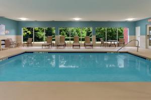 夏洛特阿罗伍德快捷假日酒店的游泳池位于酒店客房内,配有桌椅