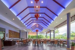 奈汉海滩Phuket La Siesta的一个带桌椅的餐厅和蓝色的天花板