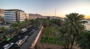 亚喀巴Nairoukh Hotel Aqaba的一条拥有汽车和棕榈树的城市街道和大海