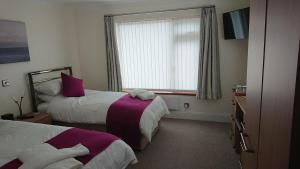 赫尔斯顿Rose Vean Bed & Breakfast的酒店客房设有两张床和窗户。