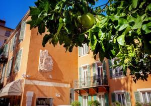 尼斯Hôtel restaurant Oasis的一座橘色的建筑,前面有一棵树