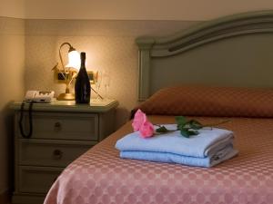 钱皮诺路易二世酒店 的床上有一瓶葡萄酒和一条毛巾