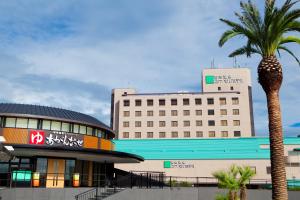 熊本其宽温泉域贝尔酒店的前面有棕榈树的建筑