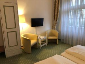 克罗伊特祖尔波斯特酒店的酒店客房配有一张床、一把椅子和一台电视。
