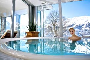 翁根Hotel Silberhorn - Residences & Spa Wengen的一位女性在一座有山背景的游泳池里