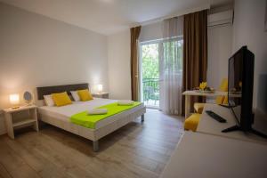莫斯塔尔Villa Odobasic Rooms的一间卧室配有一张带黄色枕头的床和电视。