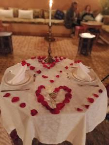 马拉喀什KOUTOBIA ROYAL的一张桌子,上面有一块蛋糕,上面有蜡烛和红玫瑰