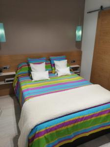 阿维拉The Little House Sir的一张大床,配有色彩缤纷的条纹床单和枕头