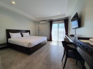 乌隆他尼T-NEE Hotel@Udon的一间卧室配有一张床和一张书桌及电视