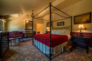 Painesville斯蒂尔庄园宾馆及集散中心的一间卧室配有一张带红色毯子的天蓬床