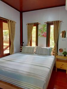 恰洛克拉姆Baan Moonchan House的卧室设有一张带窗户的白色大床