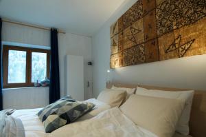 佩尔吉内瓦尔苏加纳Al Maset di TSS' - Green Apartament - Zona Living Spaziosa - Perfetto per Famiglie Numerose a Pergine Valsugana的一张带白色床单和枕头的床,靠窗