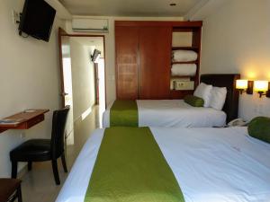 普埃布拉康科迪亚套房酒店的酒店客房,配有两张床和椅子