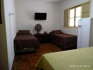 皮拉西卡巴CASA 230 - Guest House的客房设有两张床、一台冰箱和窗户。