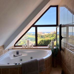 贝纳尔马德纳Luxurious duplex penthouse with golf and sea views的带浴缸的浴室和大窗户