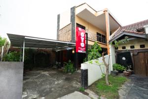 日惹Super OYO 2285 Art Guest House Syariah的前面有红色标志的房子