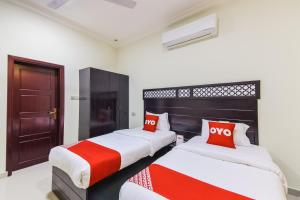 阿尔哈德Ras Al Hadd Waves Hotel的配有红色和白色枕头的客房内的两张床