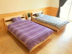 仙台HIBARI GUESTHOUSE的两张睡床彼此相邻,位于一个房间里