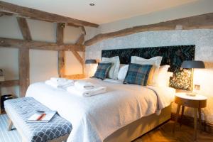 麦克尔斯菲尔德The Legh Arms Prestbury的一间卧室配有一张大床和毛巾