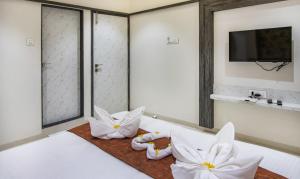 纳威孟买MEGH RESIDENCY的配有白色枕头和电视的酒店客房